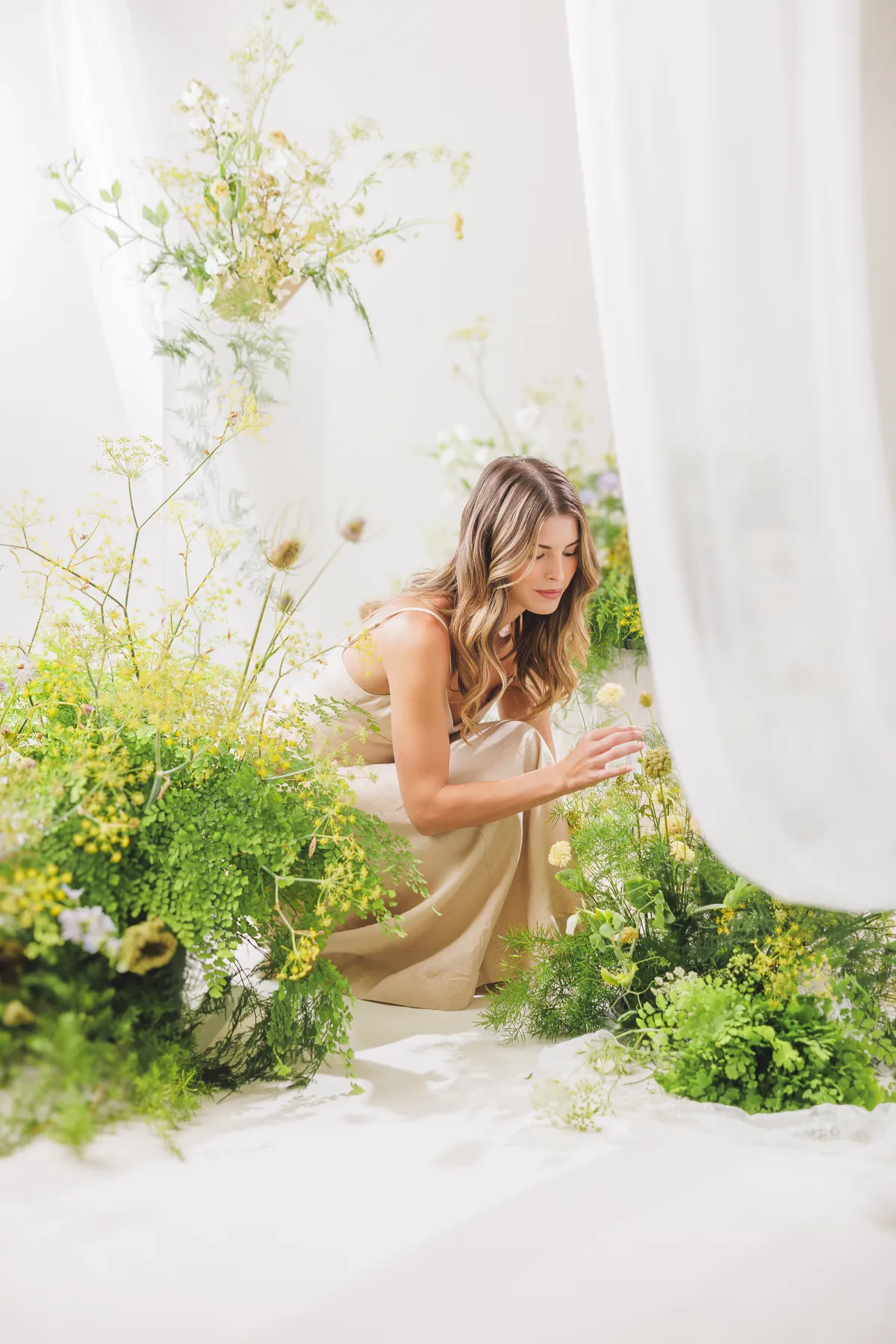 Florist arranging craspedia and greenery in a wildflower installation — Let Them Eat Flowers